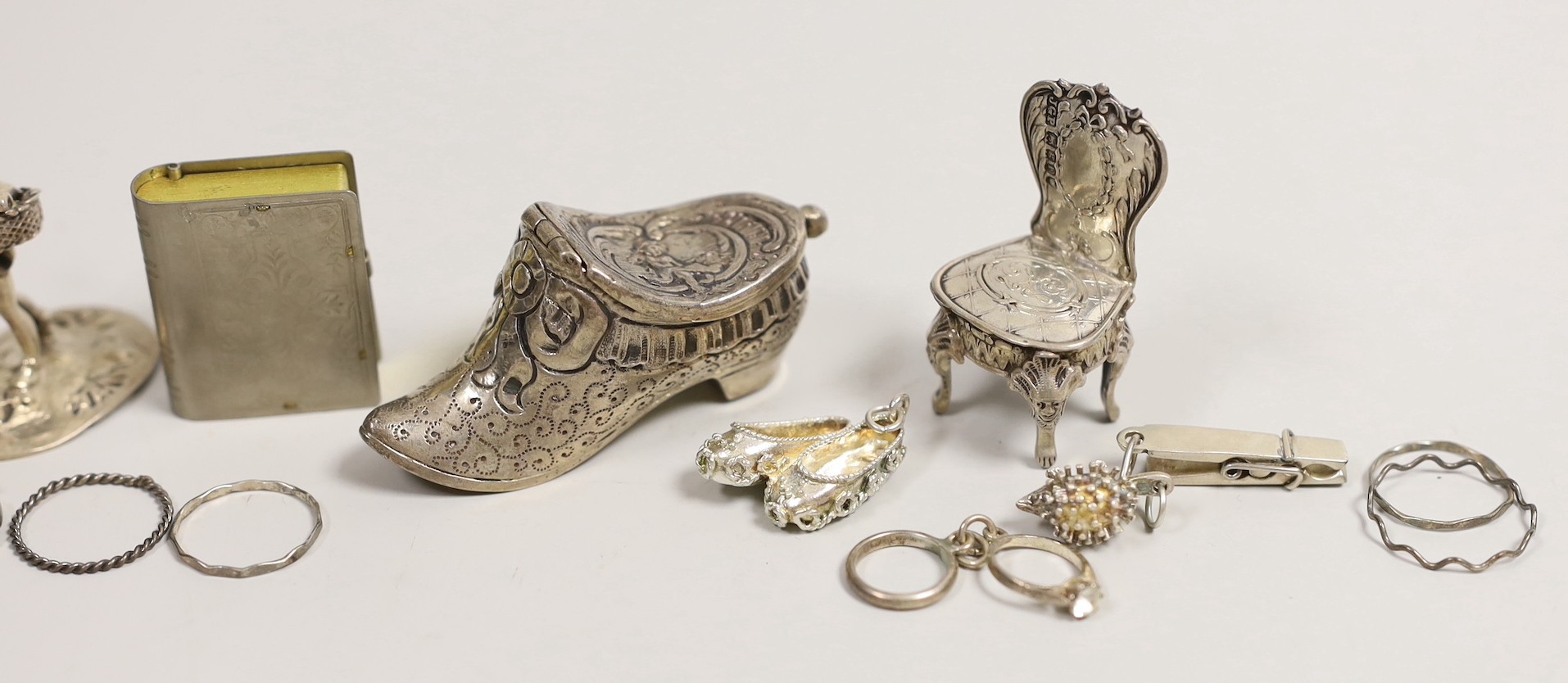 An Edwardian silver miniature model of an occasional chair, import marks for London, 1902, 43mm, a continental white metal model of a shoe and a similar model of a young child, a base metal 'book' box containing a rosary